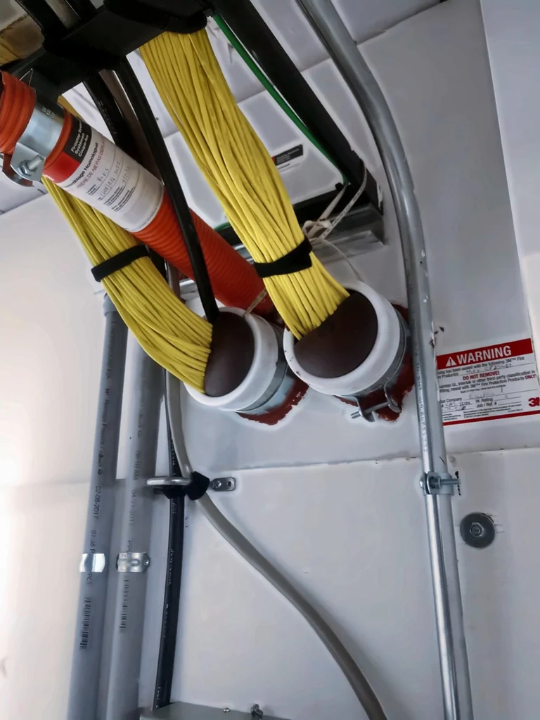 Cable bundles through firestopped sleeves with a 3M label