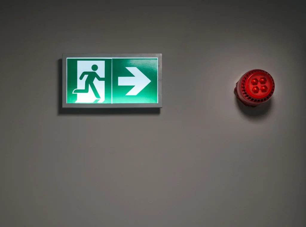 Lit exit sign and alarm in a dark corridor